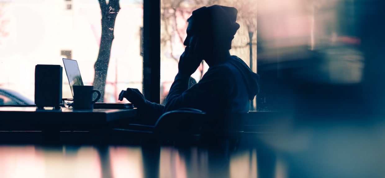 silhouette of a person sitting in front of a laptop